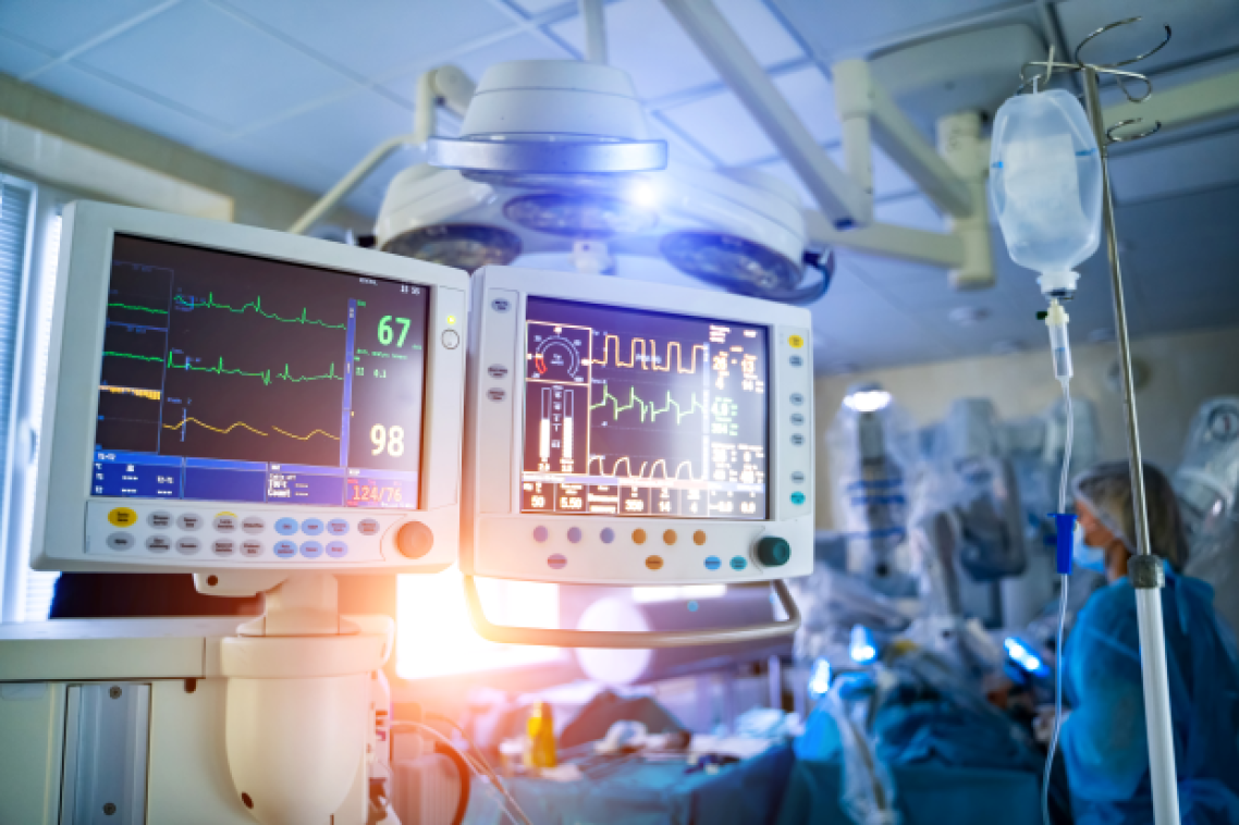 an intensive care ward in a hospital with monitoring screens and staff in blue gowns