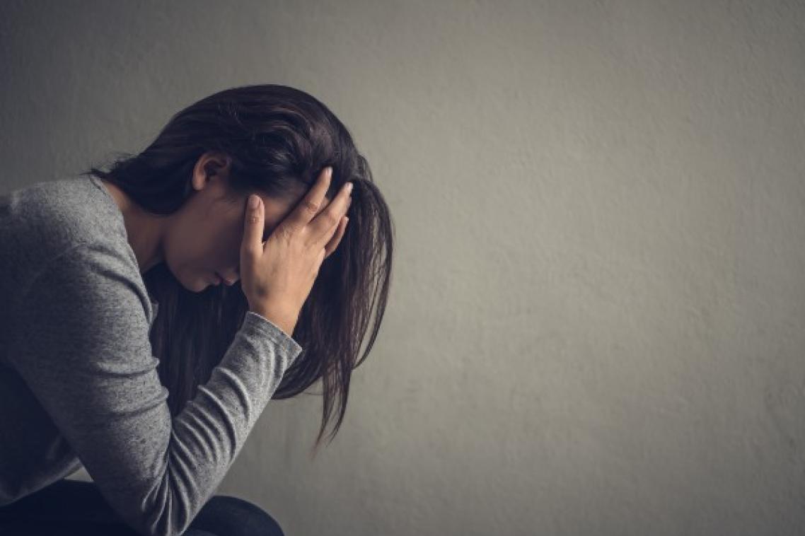 Depressed woman sitting on a chair in dark room at home. Lonly , sad, emotion concept.