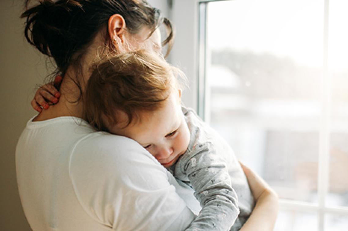 A mother holding a young toddler in her arms