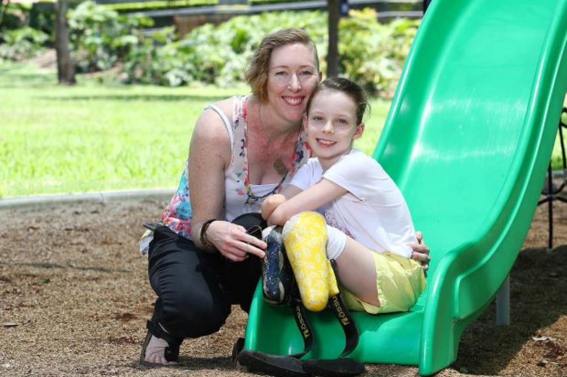 Nine year-old sepsis survivor Mia Wilkinson sitting on slide with mother Amy. Supplied.
