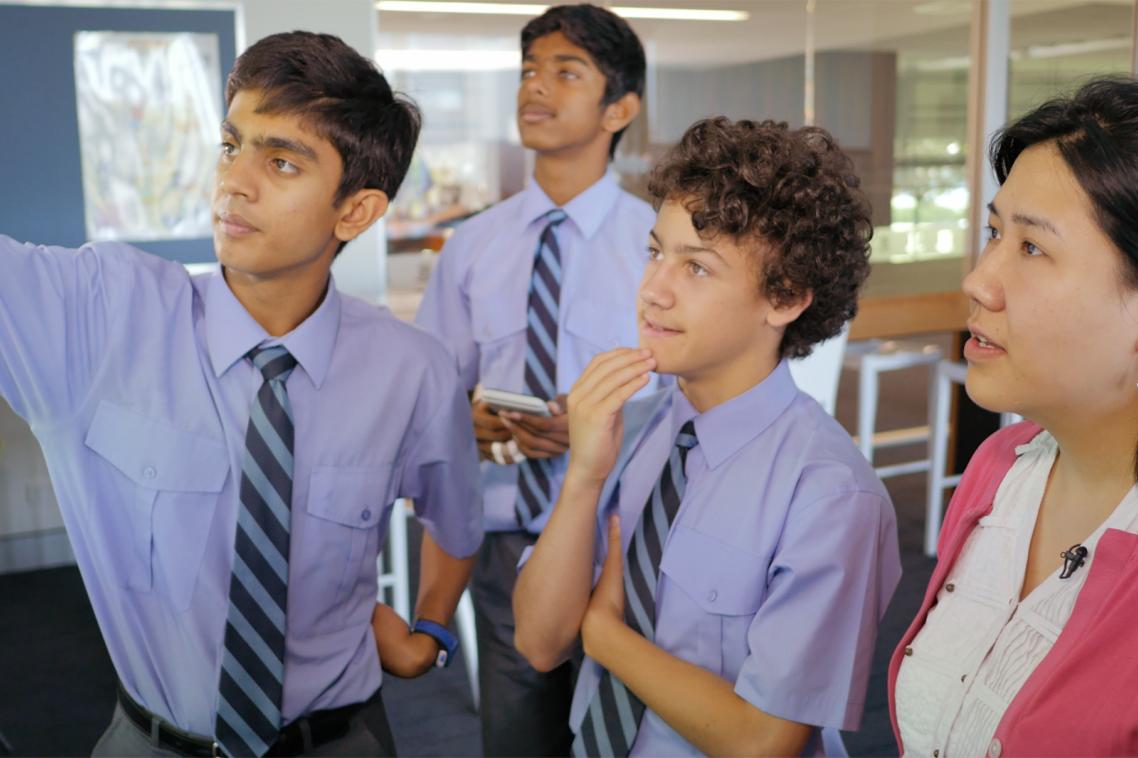 Brisbane Grammar School students with Head of Physics Noël Chan discuss the outcomes of their experiment on acceleration due to gravity.