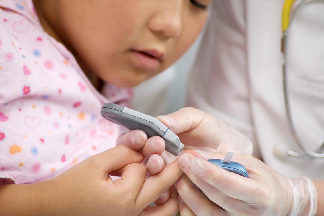 A child has a finger prick test for blood sugar levels