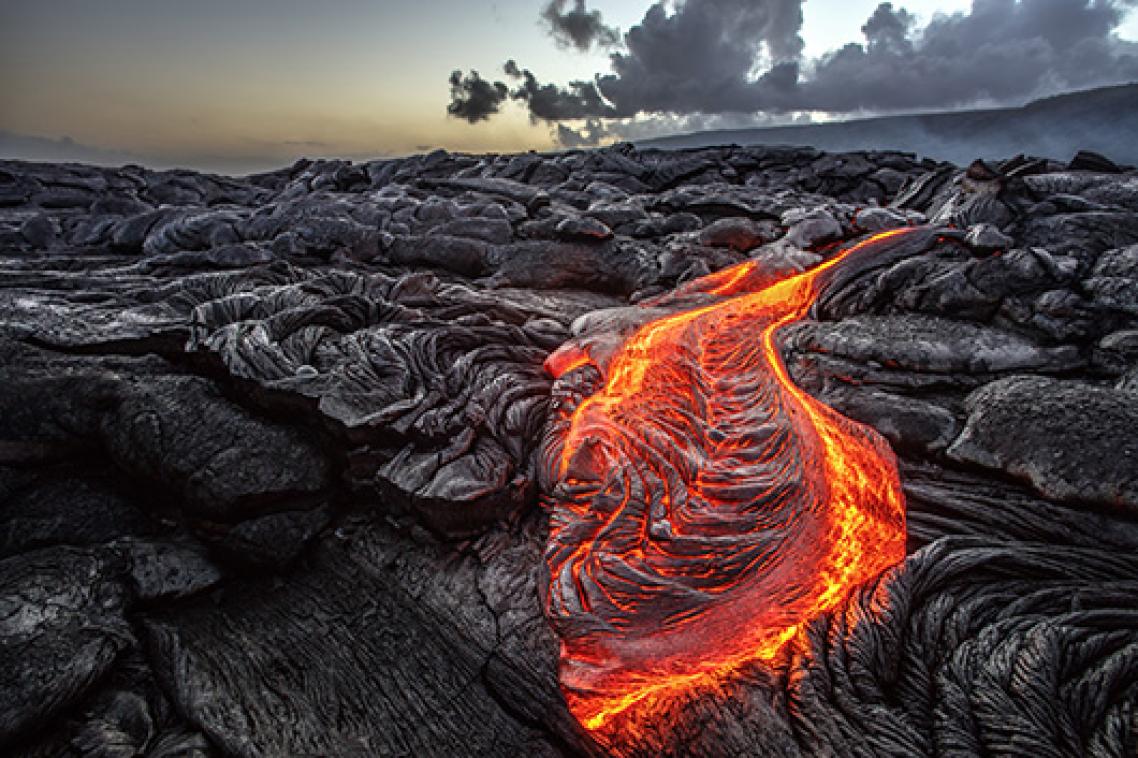 Molten lava spilling over volcanic rocks 