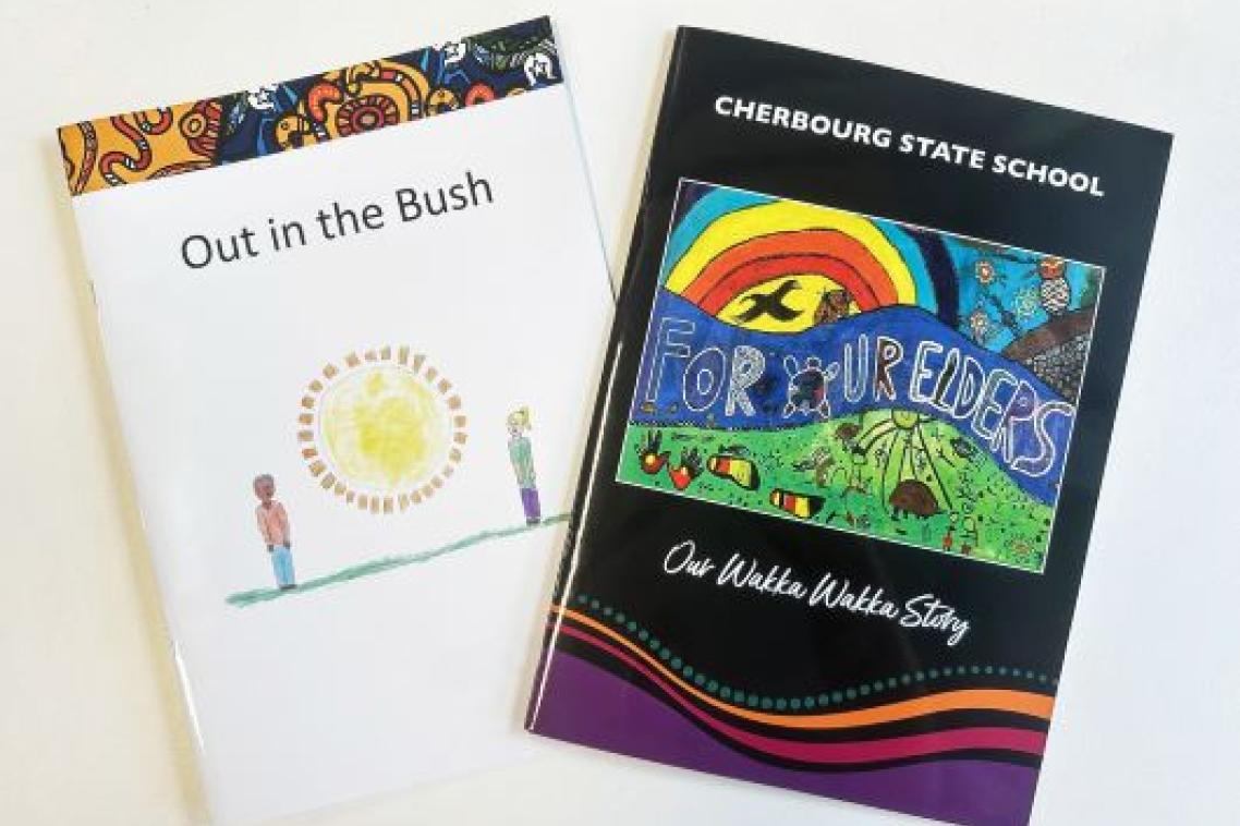 Two Indigenous story books fanned out on a white desktop. One is titled Out in the Bush, the other is For Our Elders.