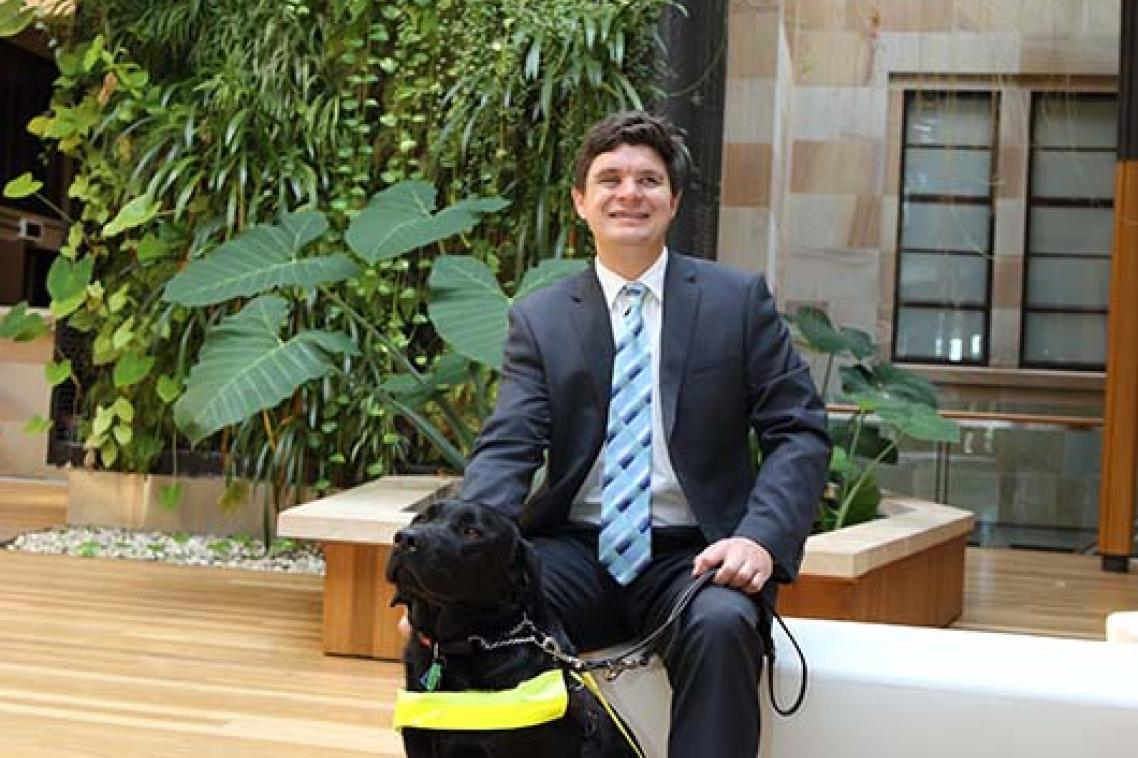 A man patting a vision assistance dog.