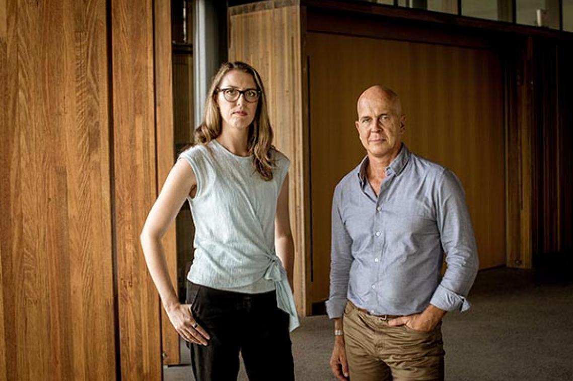 Rebecca Ananian-Welsh and Peter Greste standing next to each other in a large lobby with wooden panelling