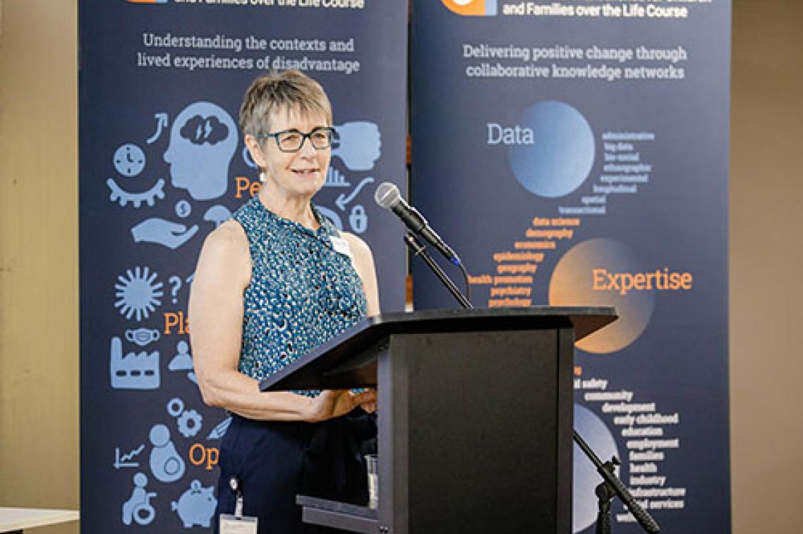 Professor Janeen Baxter standing smiling at a podium