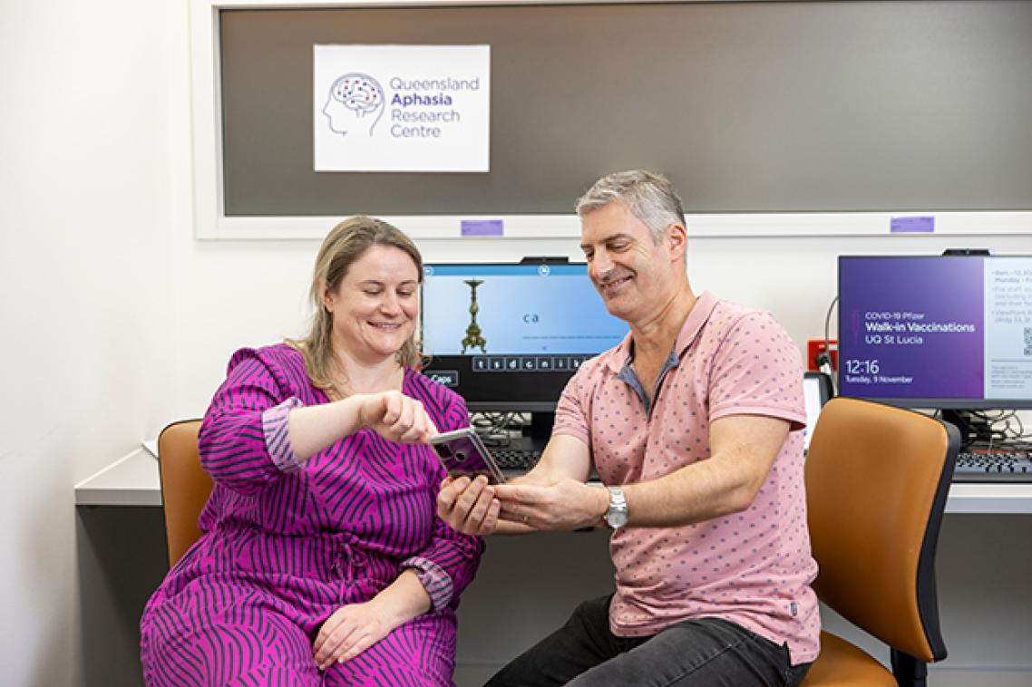 QARC researcher Jessica Campbell showing a person with aphasia an app on a phone.