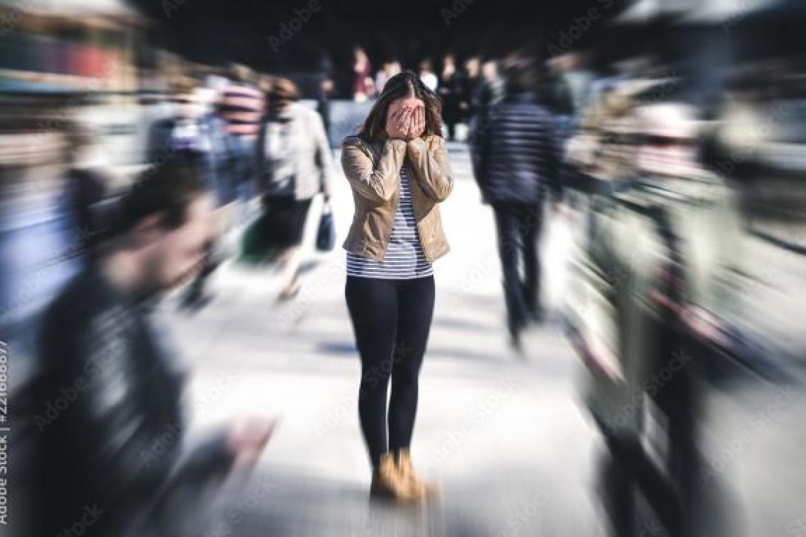 Woman standing with head in hands in middle of busy city. Adobe