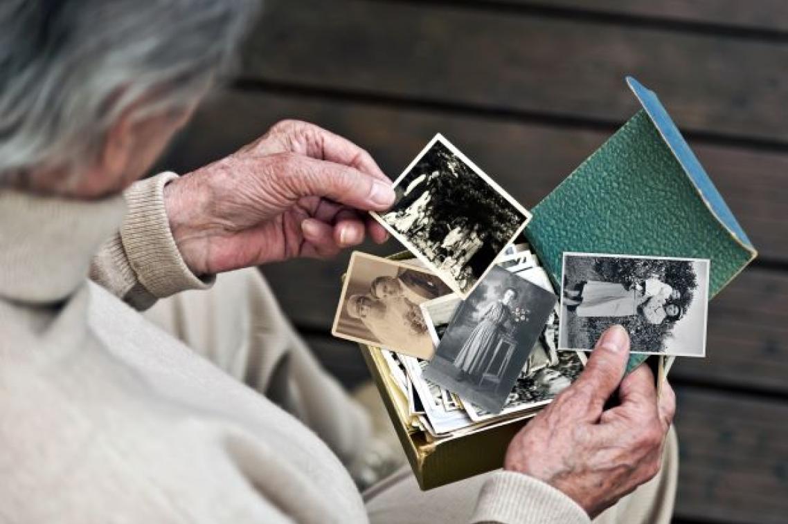 Elderly woman holding old photographs. Adobe.