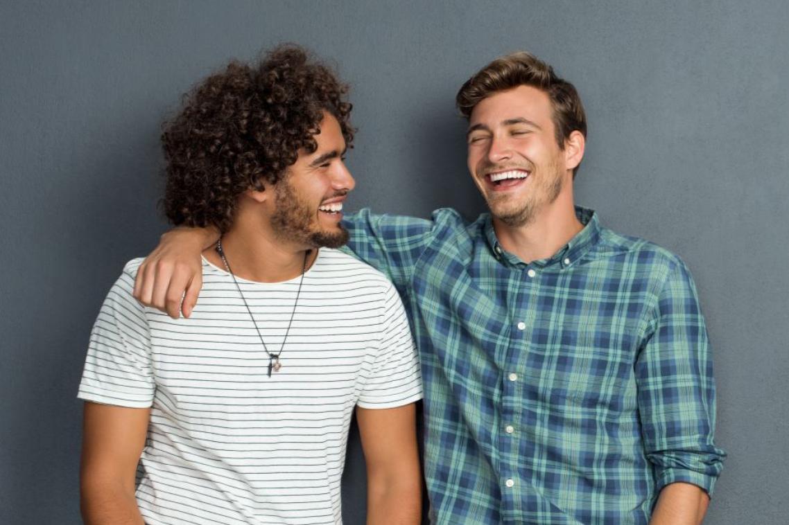 Two young men smile and joke together as friends.