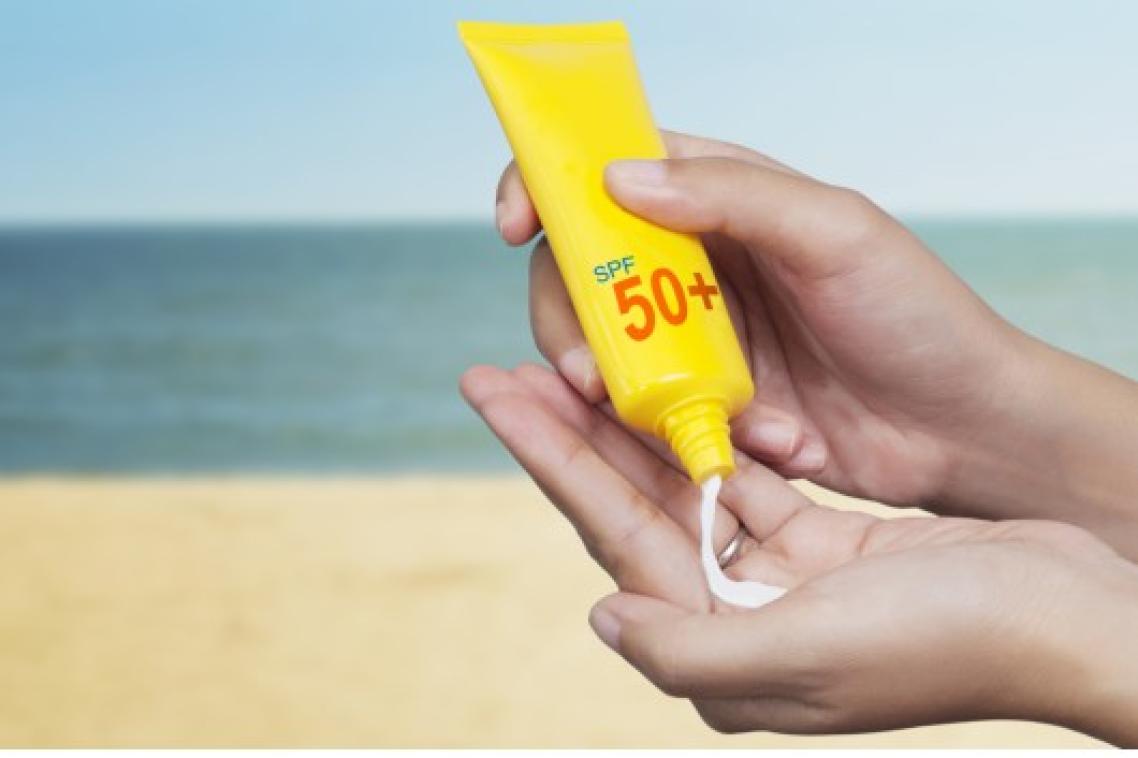 Pair of hands holding a tube of sunscreen, and squeezing some into one palm