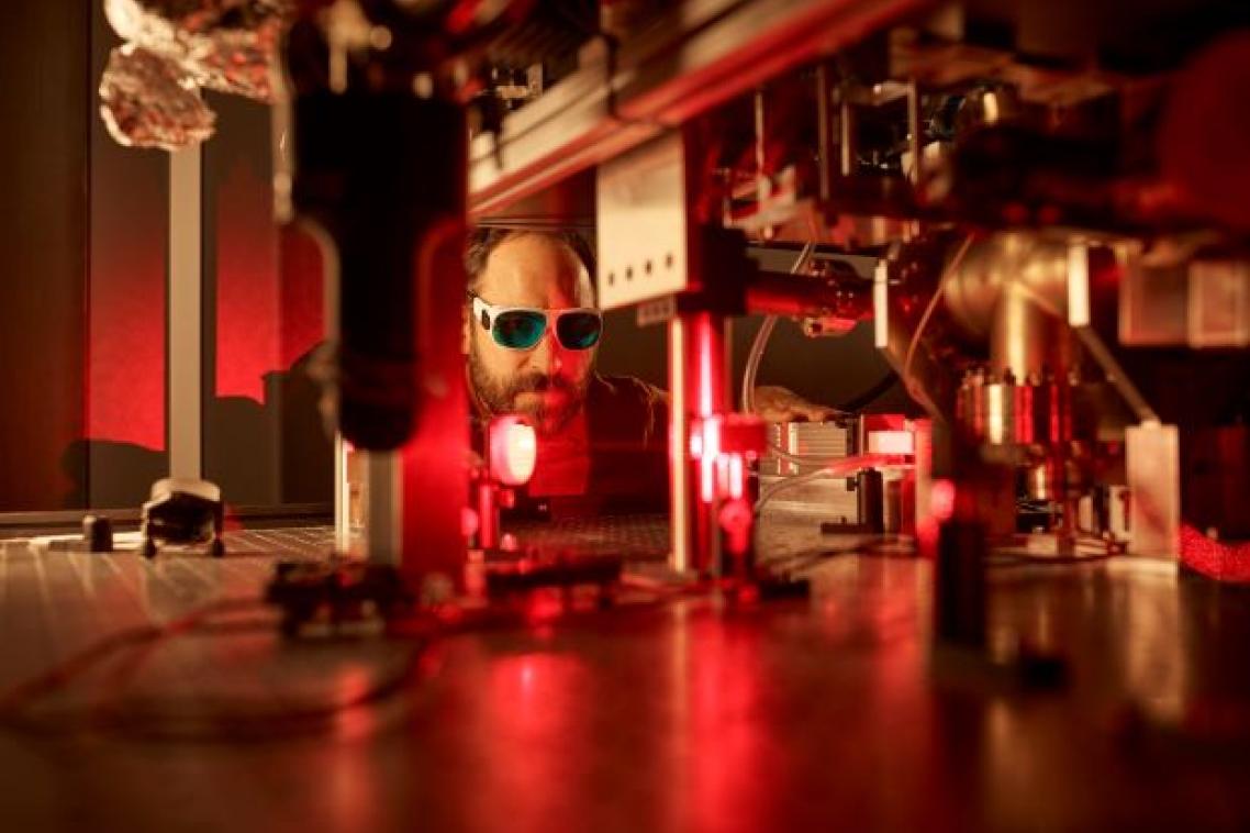 Male researcher under red light in a quantum physics lab.