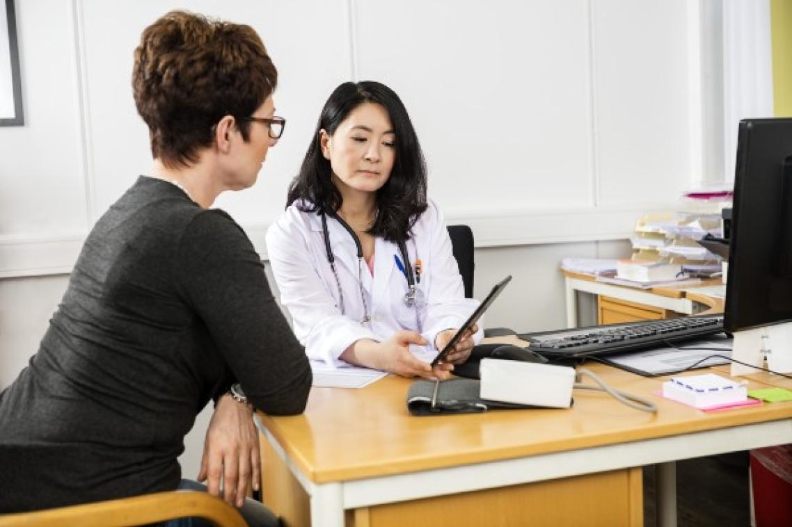 Doctor showing woman website on digital device.