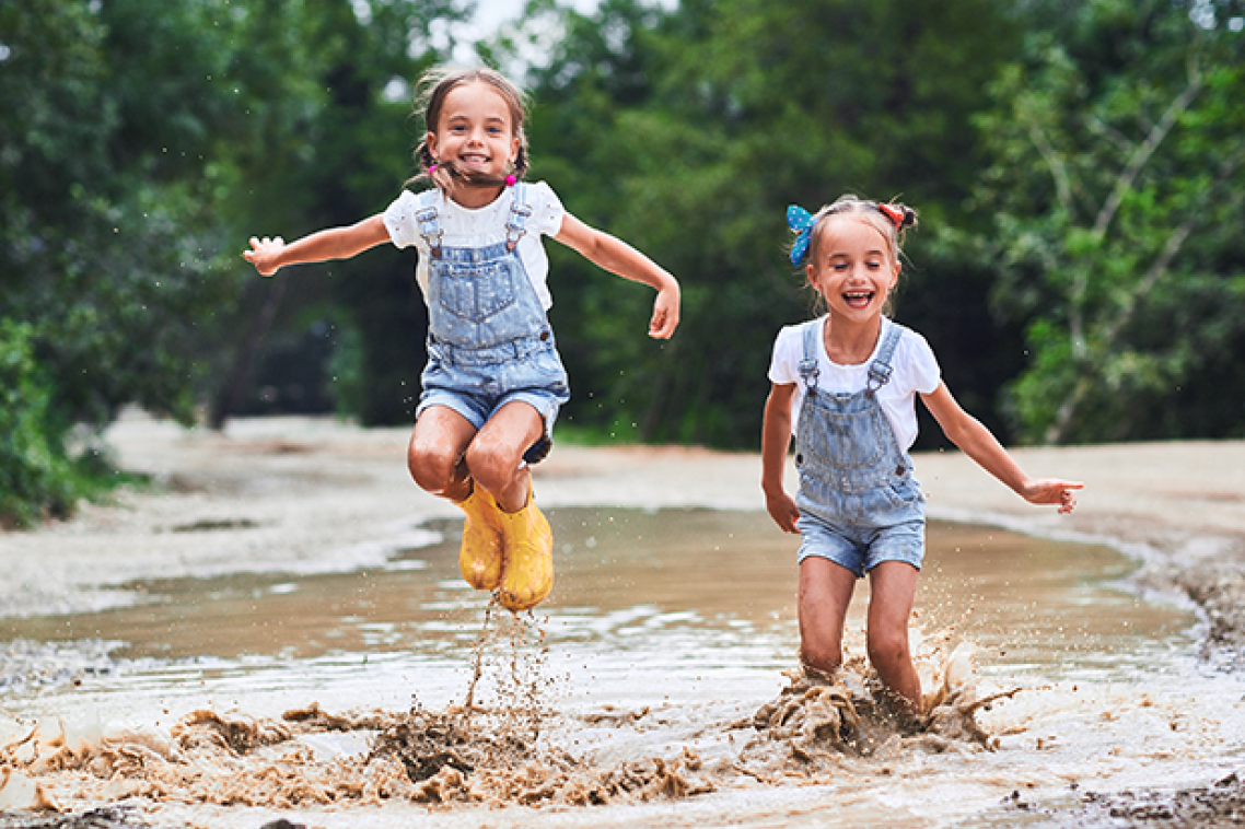 Twin girls jumping in a stream