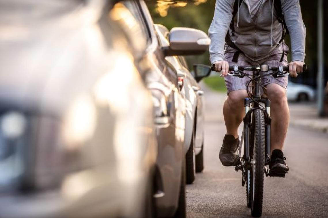 a cyclist riding close to a line of cars