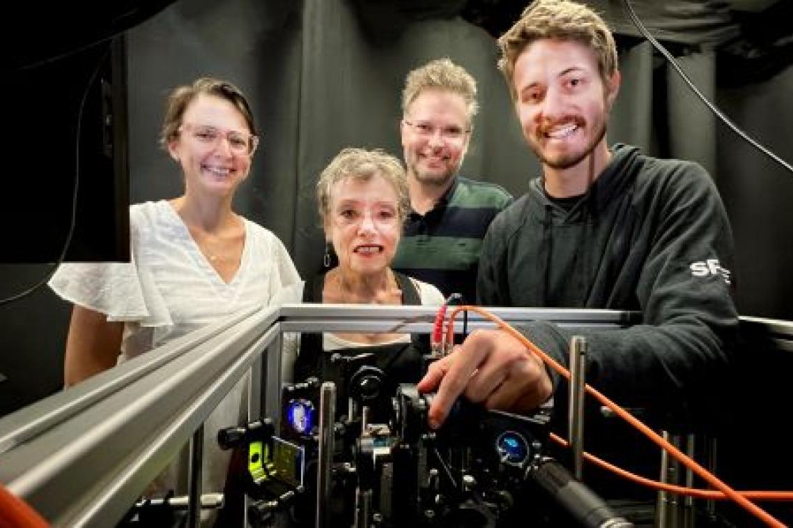 Two women and two men stand behind computer equipment