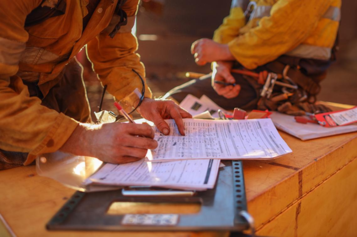 Close up of mine worker in high vis writing on a piece of paper