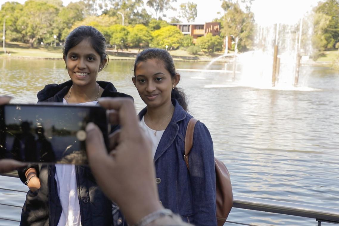Harini (L) and Abinaya getting their photo taken in front of the UQ lakes.