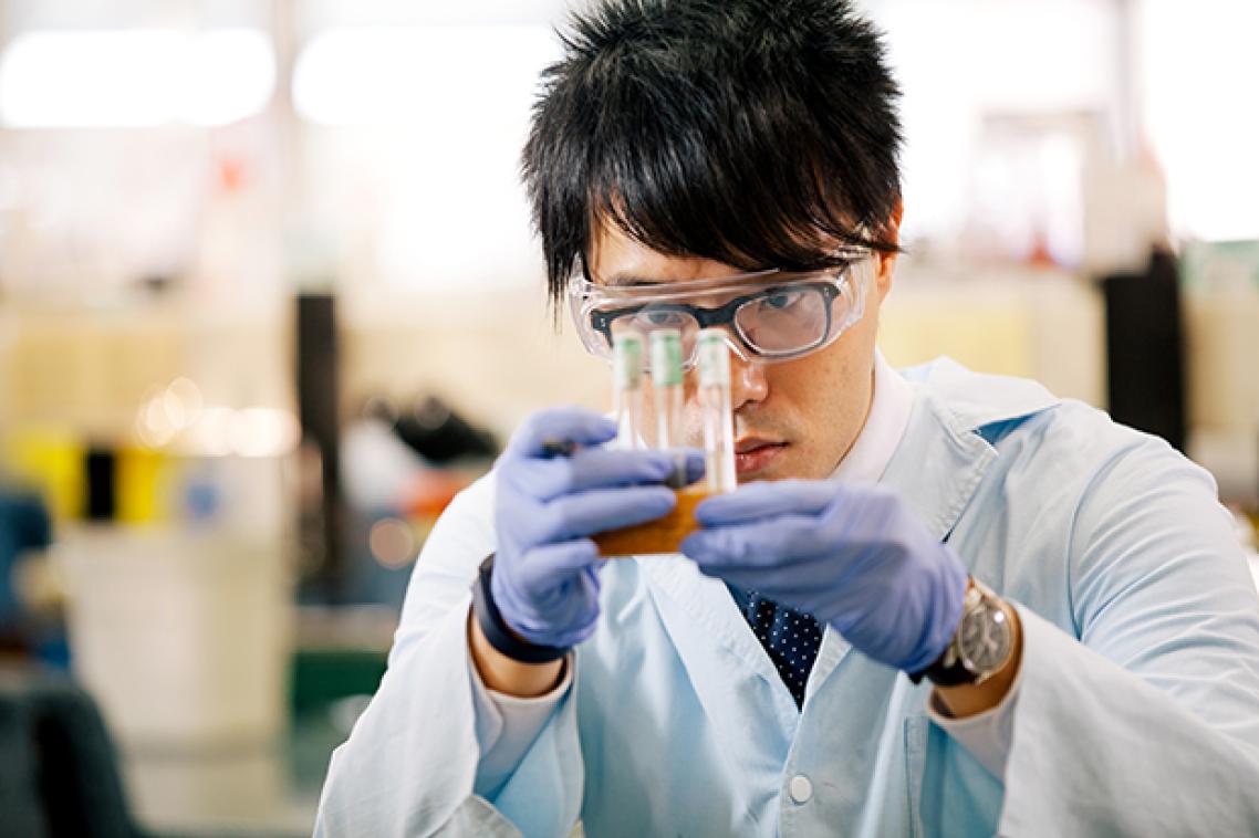 Jack Wang studies three test tubes in a holder in a laboratory