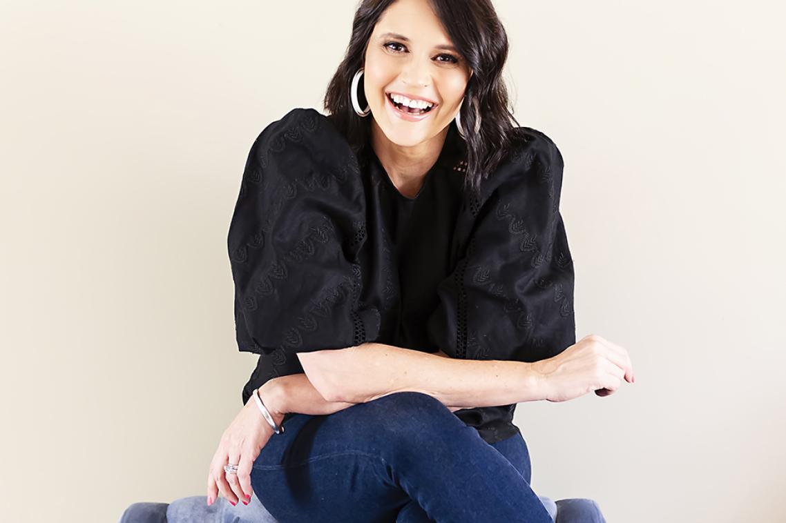Photo of Sharlene Allsopp sitting on top of a purple-coloured armchair with her arms crossed across her crossed legs