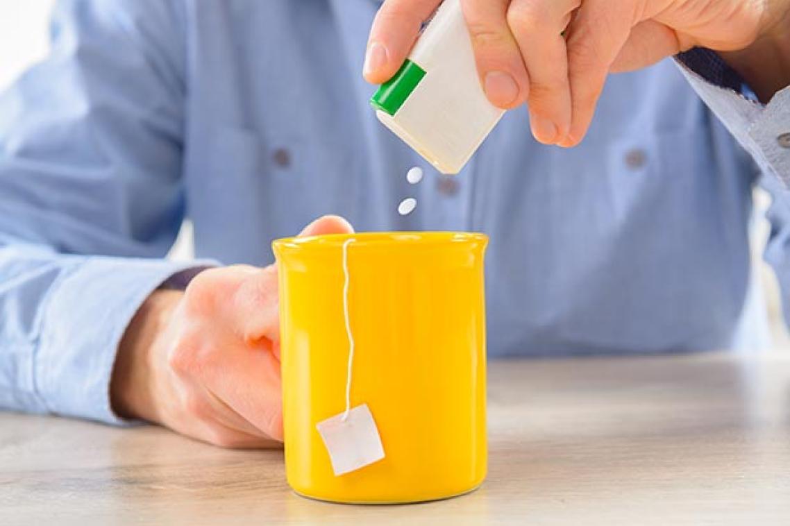 A man adds artificial sweetener tablets to a mug of tea