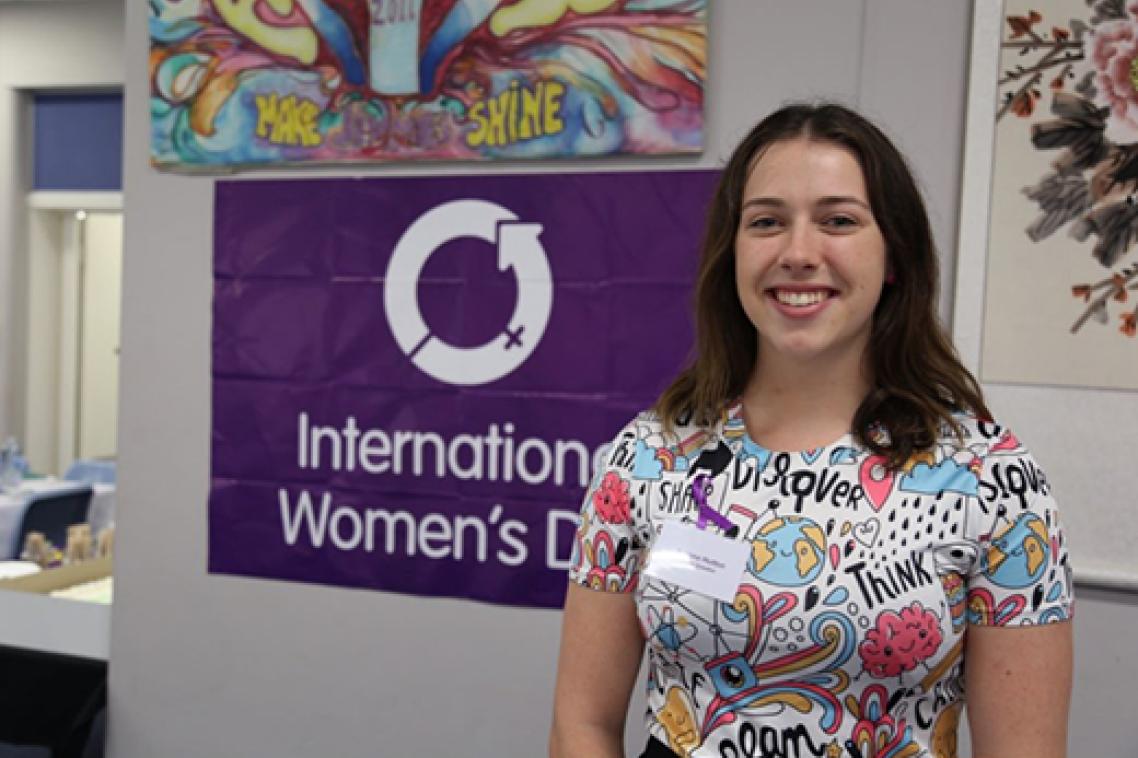 Woman standing in front of a purple sign.