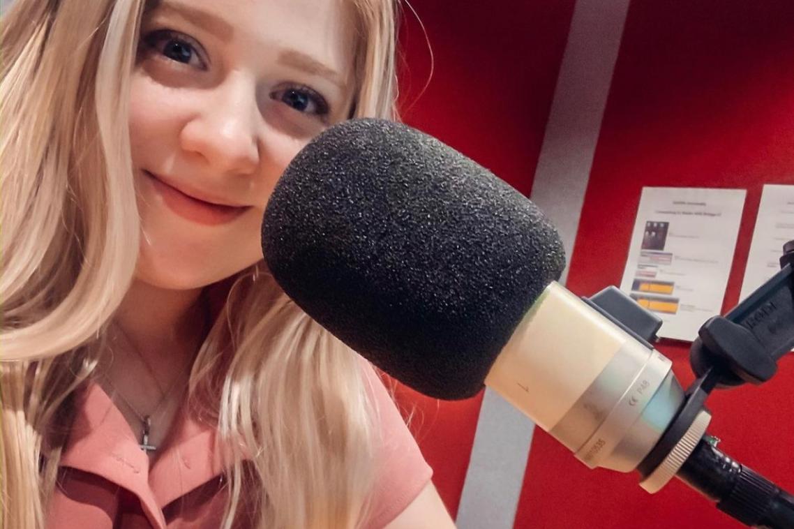 Woman sitting in front of a microphone smiling.