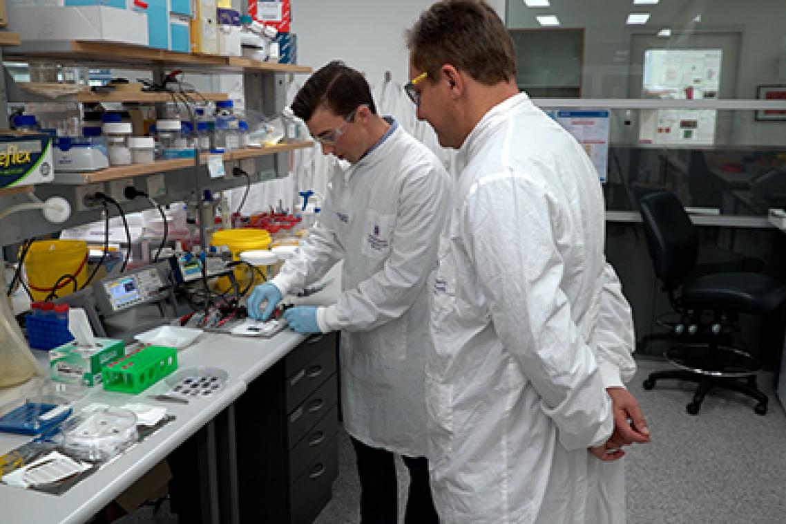 Prof Matt Trau standing in the lab with Dr Alain Wuethrich looking at the tiny chips