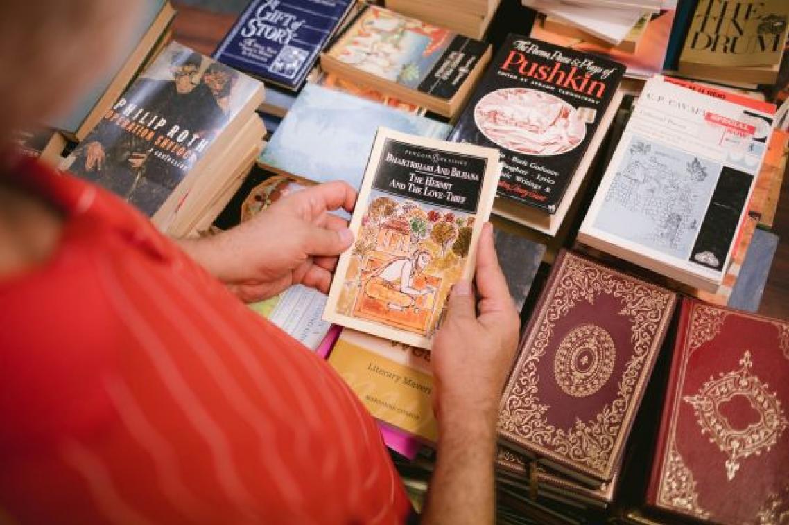 Woman holding old book with other books in background at Book Fair.