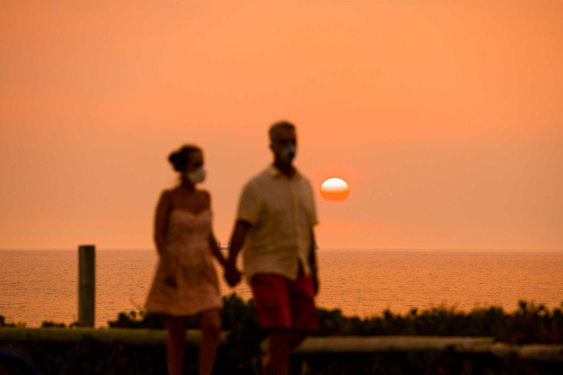 Two people standing beneath a smoggy orange sky