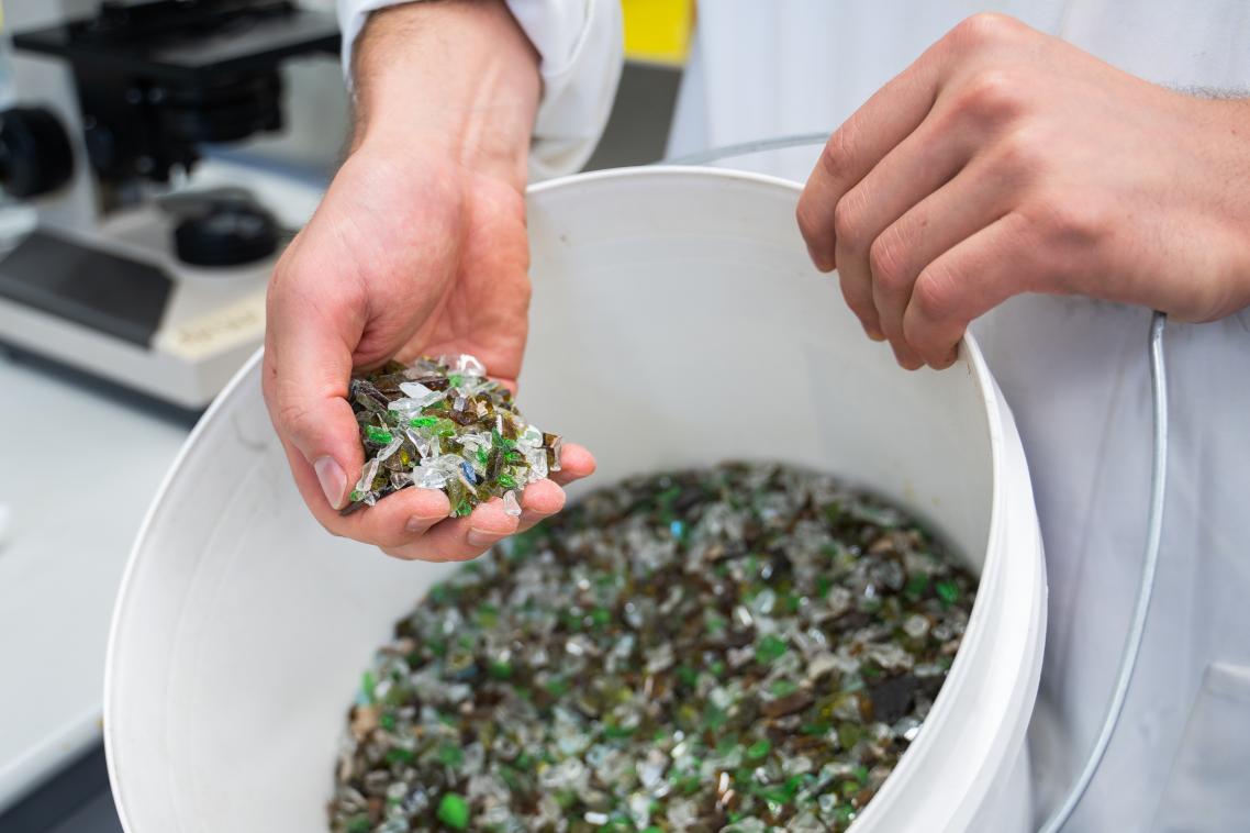 A bucket of mixed colour broken glass which can be used in the process.