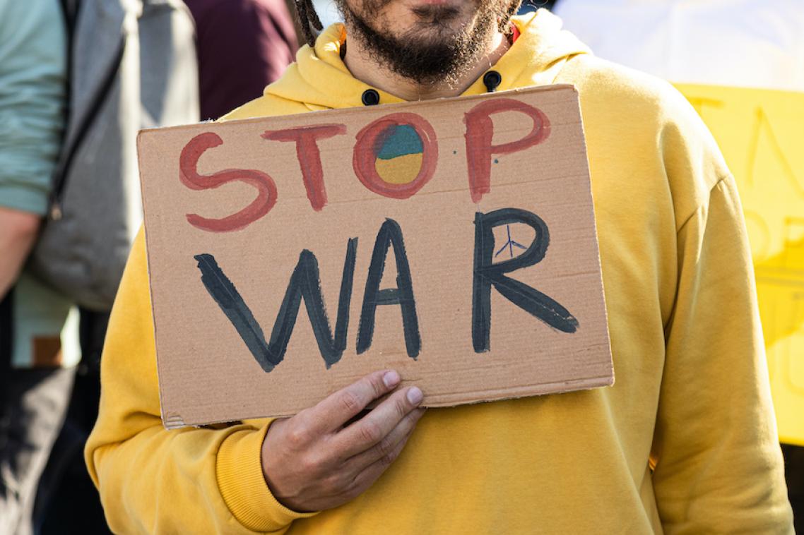 A protested with a sign that says stop war, relating to Russia's invasion of Ukraine