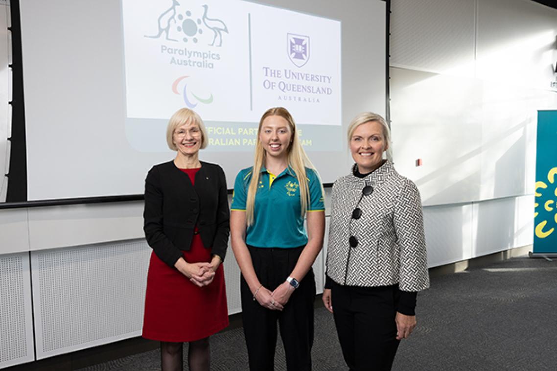 Three women standing in front of a screen displaying corporate logos
