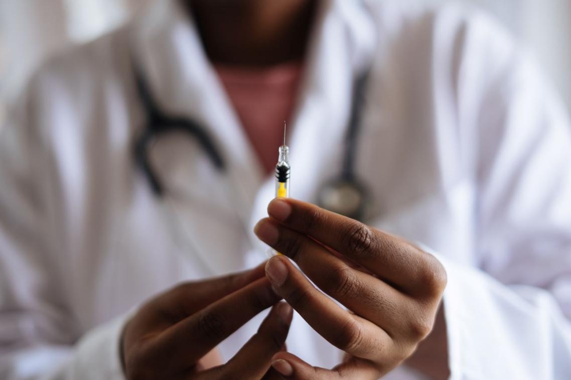 Physician in white coat holding a syringe containing vaccine