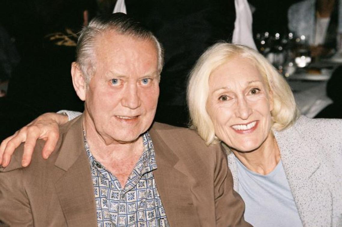 A man and woman sit side by side, smiling.