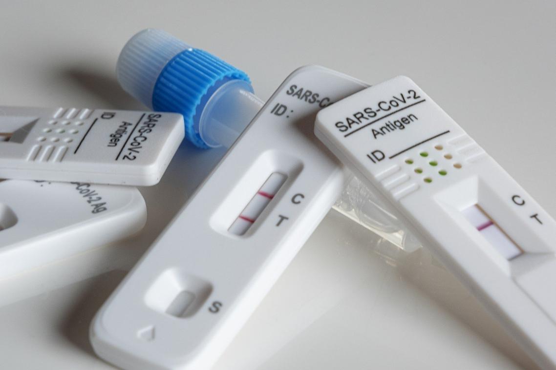 Used rapid antigen tests in a pile show positive and negative results.