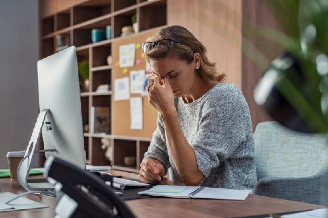 A woman in a grey sweater looking frustratingly at her computer