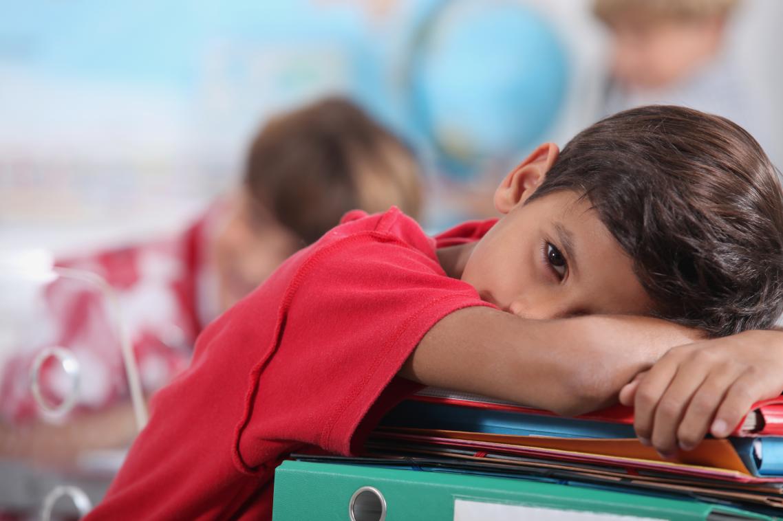 Young boy resting his head on books