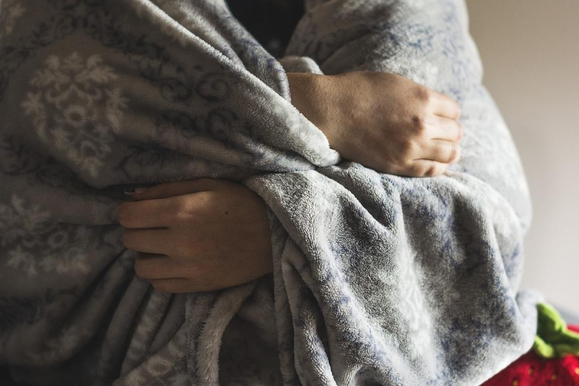 Man holding blanket around his upper body