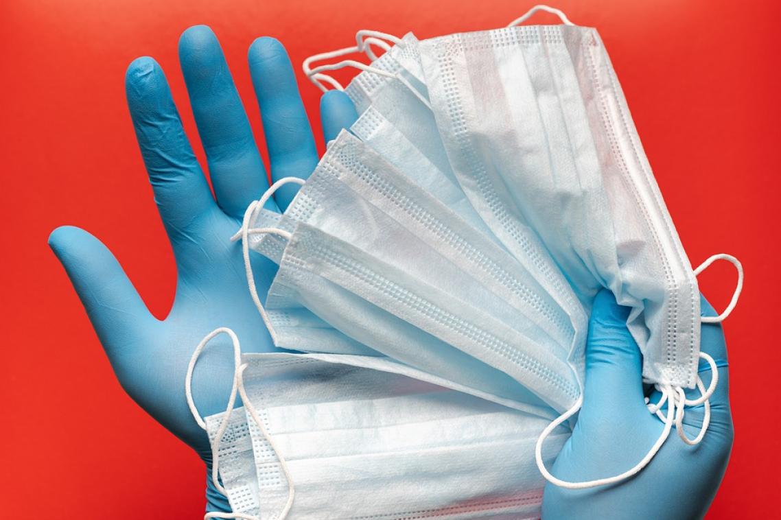 hand wearing surgical gloves and holding face masks