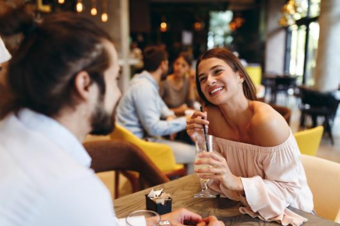 A man and a woman on a date, the woman holding a drink