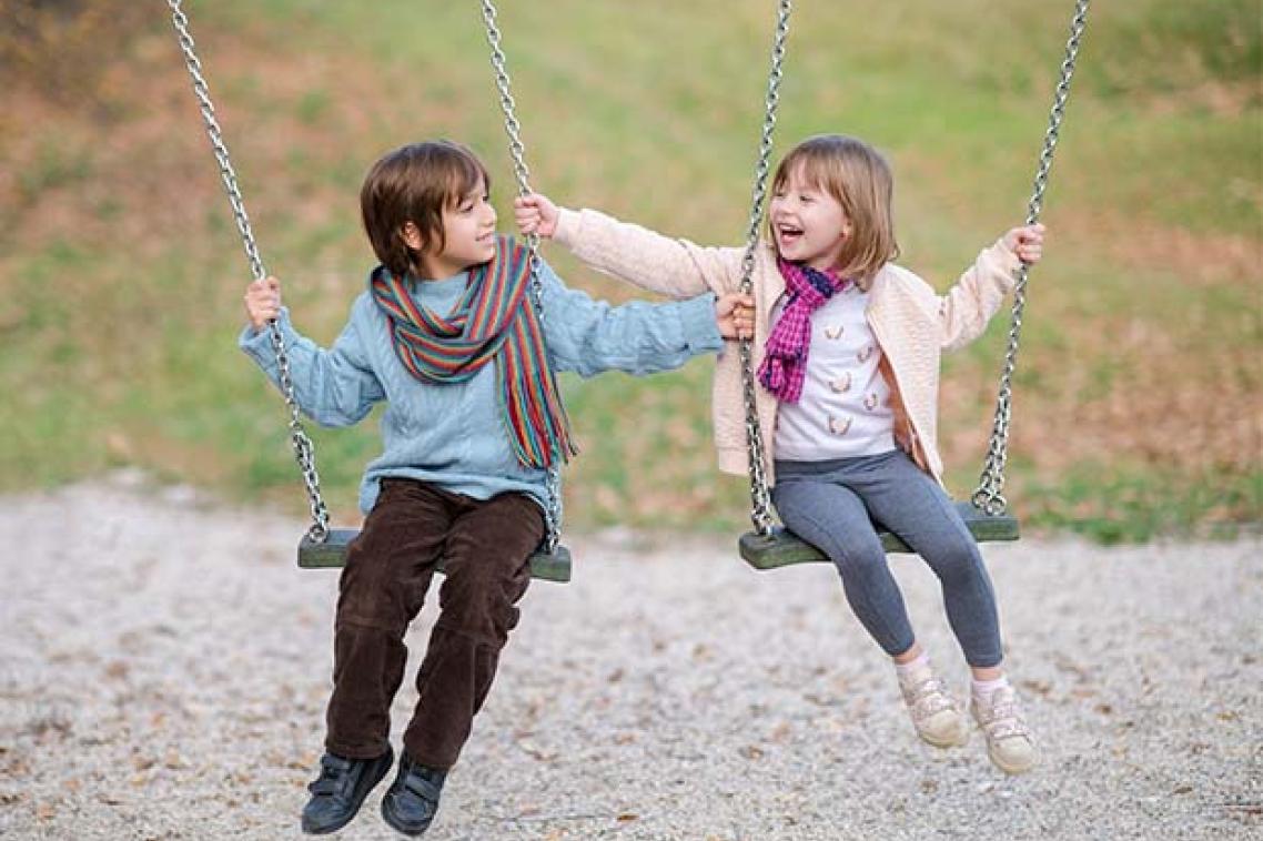 A boy and a girl swinging on swings