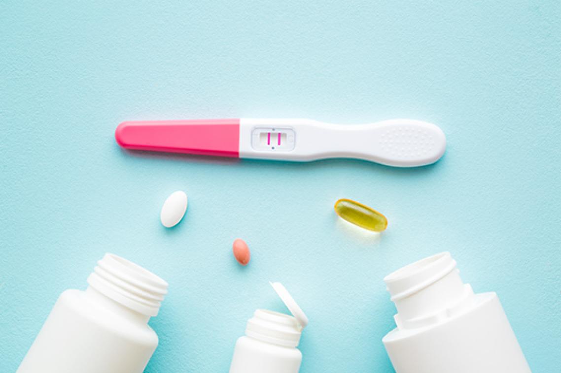 A positive pregnancy test with three pill bottles laying on their sides