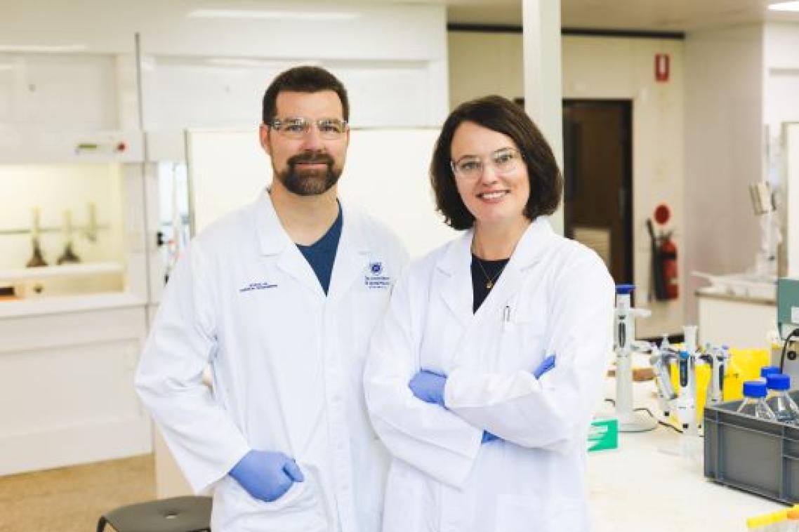 Two scientists in a lab wearing white lab coats 