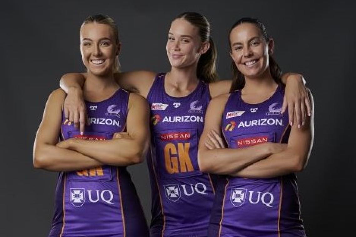 3 Firebirds players dressed in their purple netball uniforms smiling.