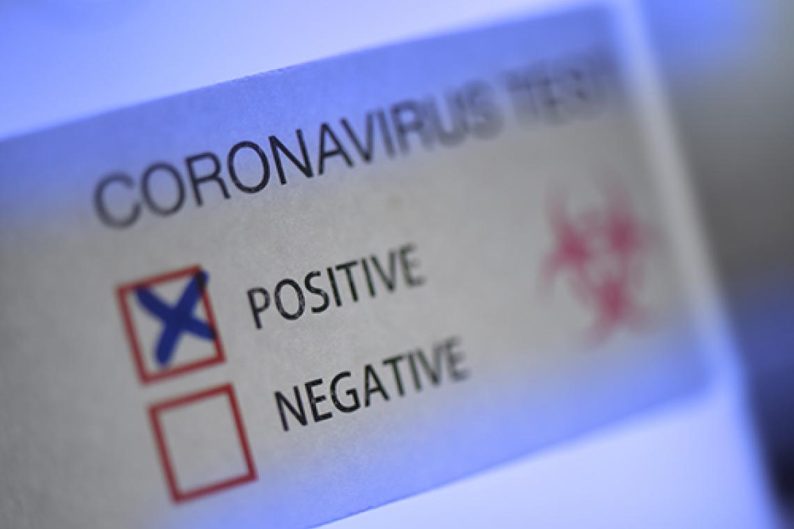 Label with a red box with a cross in it, indicating a positive COVID test result