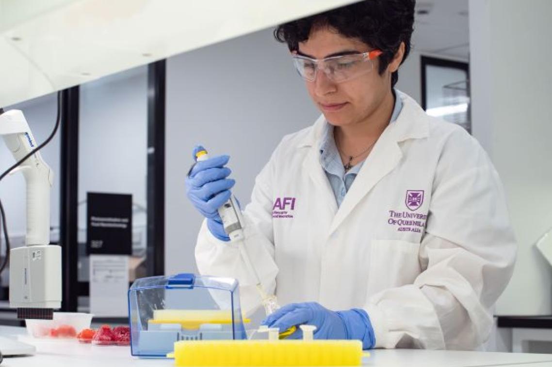 A woman wearing a lab coat doing an experiment in a science lab.