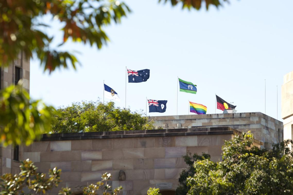 The rainbow flag flies alongside the Australian and Aboriginal Flags on top of UQ's Forgan Smith building.