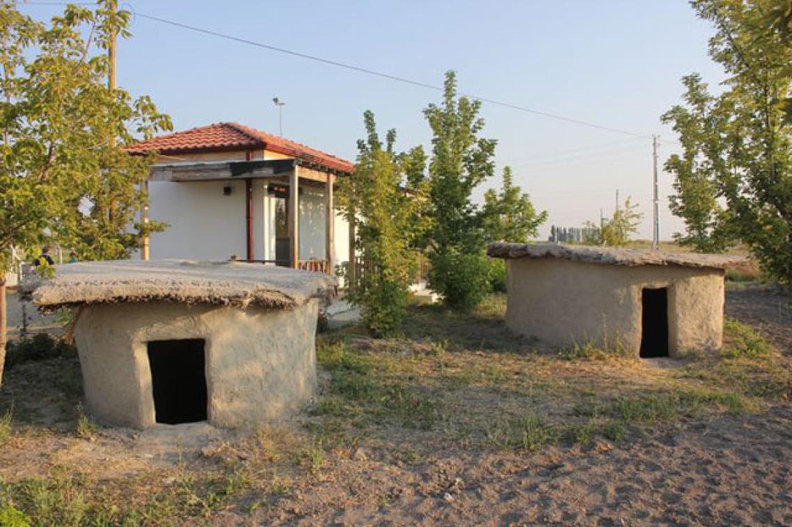 Reconstructed houses in their final form, with a visitor's centre in the background.